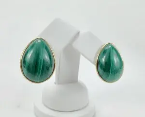Green teardrop earrings on white stand.