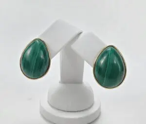 Green teardrop earrings on white stand.