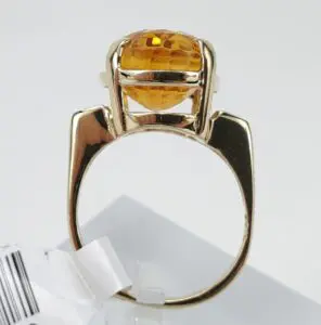 Gold ring with round orange gemstone.