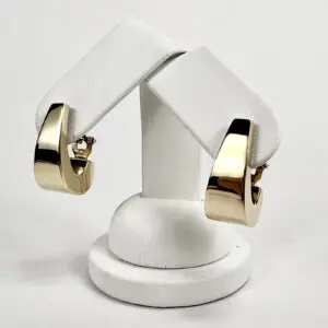 Gold hoop earrings on white stand.