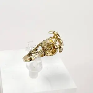 Gold scorpion ring on display stand.