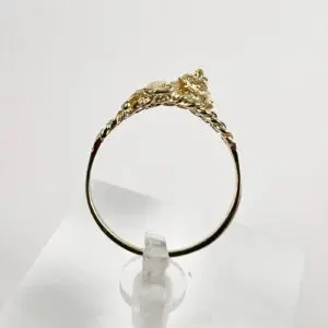 Gold ring with intricate design on stand.