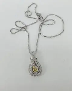 Silver necklace with a yellow gemstone pendant.
