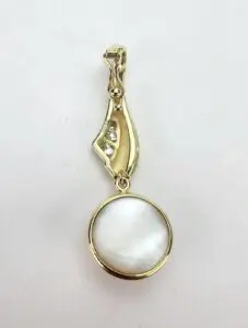 Gold pendant with round white stone.
