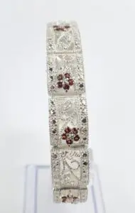 Ornate silver bracelet with red gemstones.
