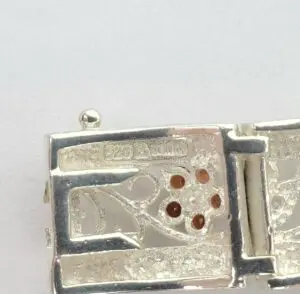 Silver clasp with floral and gemstone design.