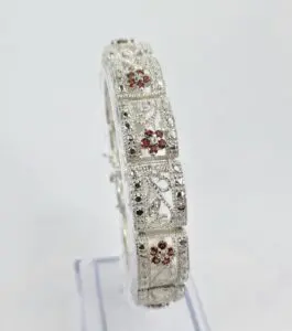 Ornate silver bracelet with red gemstones.