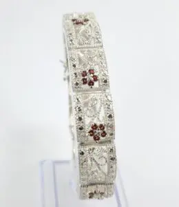 Ornate silver bracelet with red gemstones.