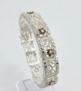 Ornate silver bracelet with red gemstones.