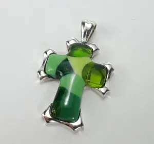Green and silver cross pendant on white.