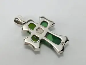 Silver cross pendant with green accents.