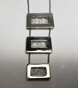 Geometric silver pendant with rectangular designs.