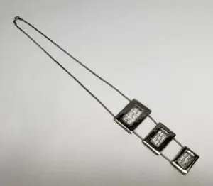 Geometric silver necklace with three square pendants.