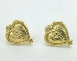 Gold heart-shaped earrings with cupid design.