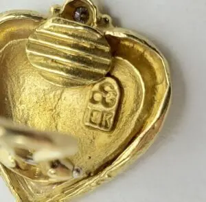 Gold heart-shaped pendant with engraved markings.
