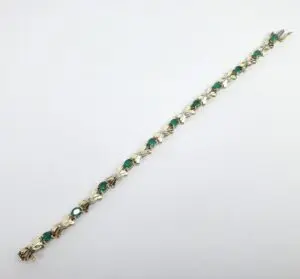 Gold bracelet with green gemstones, white background.