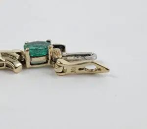 Gold pendant with green gemstone centerpiece.