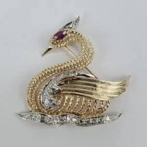 Gold swan brooch with gemstone details.