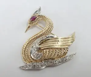 Gold swan brooch with jeweled accents.