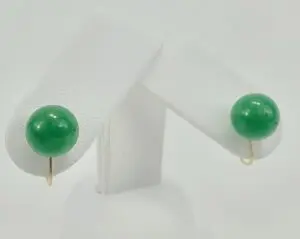 Green jade earrings on white display stand.