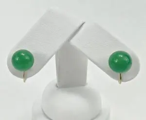Green gemstone stud earrings on white stand.