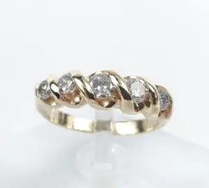 Gold ring with diamonds on display stand.
