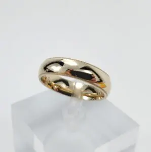 Gold wedding ring on display stand.