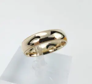 Gold wedding band on display stand.