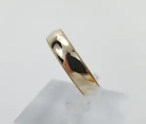 Gold ring with reflective surface on stand.