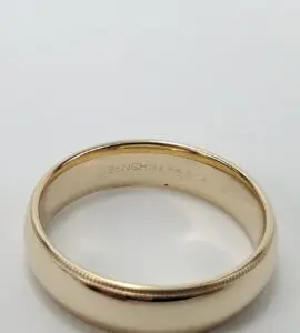 Gold wedding band with engraved interior text.