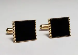 Gold and black square cufflinks on display.