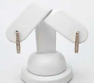 Gold diamond earrings on white display stand.