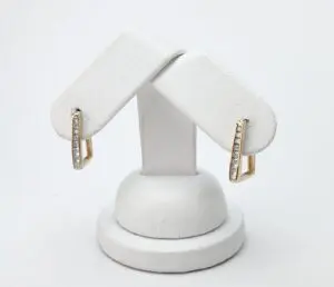 Gold earrings with diamonds on white stand.