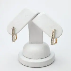 Gold earrings with diamonds on white stand.
