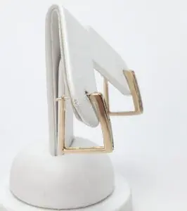 Gold square hoop earrings on display stand.