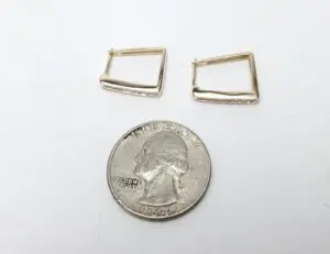 Gold earrings beside a U.S. quarter.