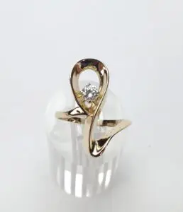 Gold ring with diamond on display stand.