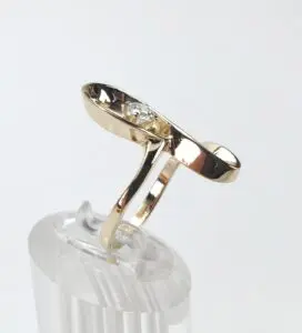 Gold ring with diamond on display stand.