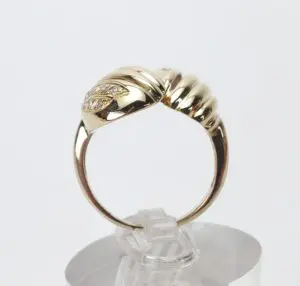 Gold ring with diamond accents on stand.