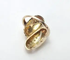 Gold-tone abstract brooch with curved design.