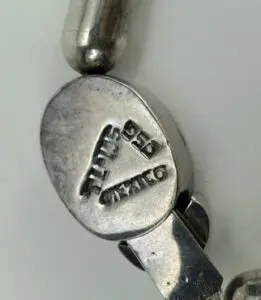 Silver clasp with engraved markings and text.