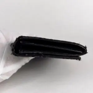 Black wallet held by a gloved hand.
