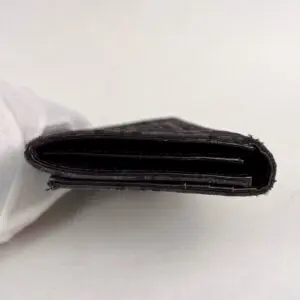 Black wallet held by gloved hand.