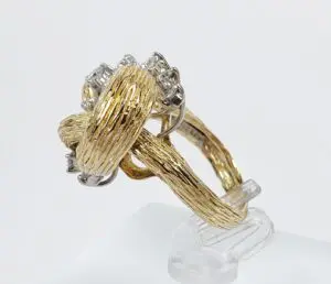 Gold textured ring with diamonds on stand.