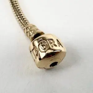 Gold bracelet with engraved letters and logo.