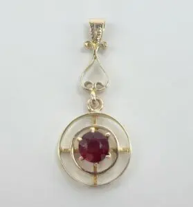 Gold pendant with red gemstone center.