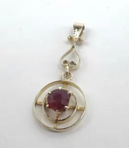 Gold pendant with a red gemstone center.