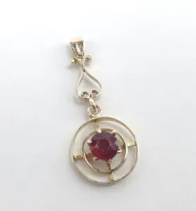 Gold pendant with a red gemstone centerpiece.