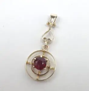 Gold pendant with red gemstone center.