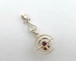 Gold pendant with circular red gemstone design.
